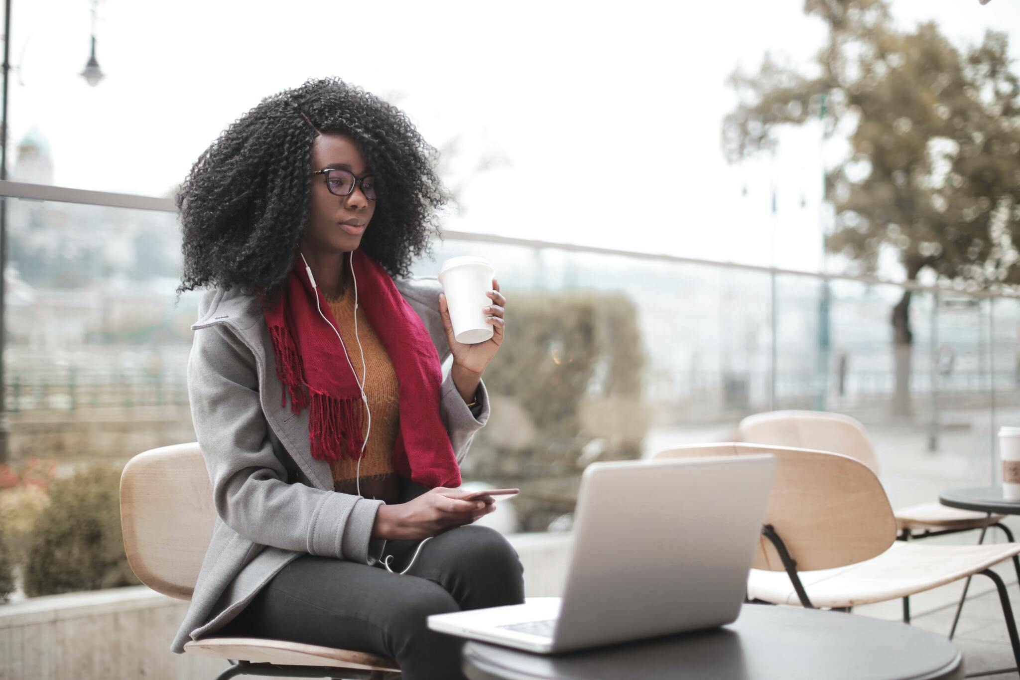 Woman doing work on her laptop while holding coffee